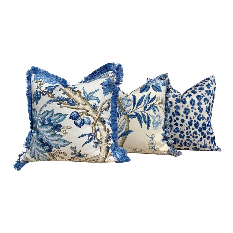 Pu&ograve; includere: Tre cuscini decorativi con motivi blu e bianchi. I cuscini hanno un bordo a frangia blu e presentano un motivo floreale, un motivo a foglie e un motivo astratto blu e bianco.