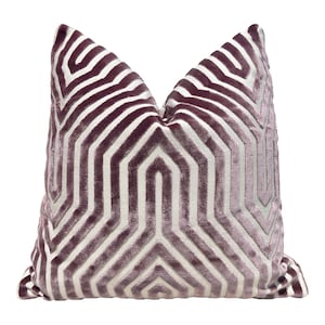 May include: A decorative pillow with a geometric pattern in shades of purple and white. The pillow is made of a soft, velvety fabric.