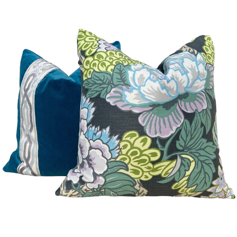 May include: Two decorative throw pillows, one with a teal velvet fabric and a white and gray patterned border, and the other with a black background and a floral pattern in shades of green, blue, and purple.