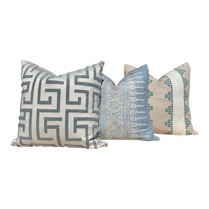 May include: Three decorative throw pillows with different patterns. One pillow has a geometric design in light blue on a cream background. Another features a blue and white pattern, and the third has a teal and cream design.
