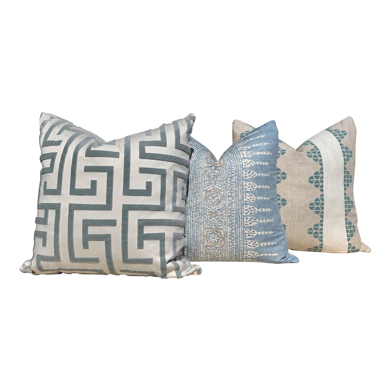 May include: Three decorative throw pillows with different patterns. One pillow has a geometric design in light blue on a cream background. Another features a blue and white pattern, and the third has a teal and cream design.