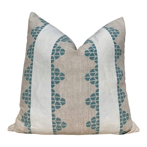 May include: A square decorative pillow with a neutral beige background. Two vertical white stripes run down the center, flanked by teal-colored, stylized floral patterns. The pillow is a soft, inviting home decor item.