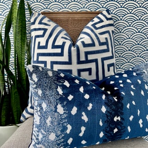 Pu&ograve; includere: Due cuscini decorativi con motivi blu e bianchi. Il cuscino superiore ha un motivo geometrico, mentre il cuscino inferiore ha un motivo astratto blu e bianco.