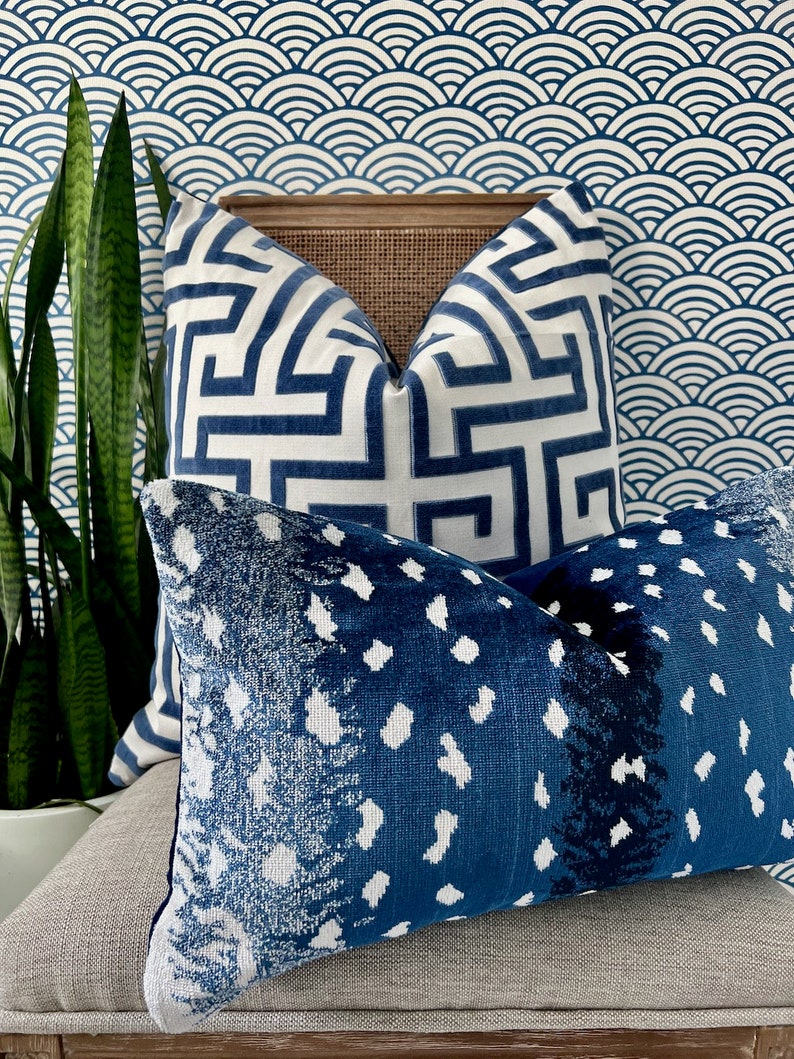 Pu&ograve; includere: Due cuscini decorativi con motivi blu e bianchi. Il cuscino superiore ha un motivo geometrico, mentre il cuscino inferiore ha un motivo astratto blu e bianco.