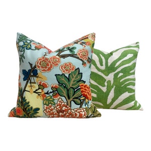 May include: Two decorative throw pillows, one with a floral pattern on a light blue background and the other with a green and white zebra print.