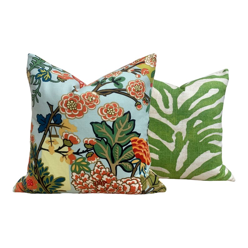 May include: Two decorative throw pillows, one with a floral pattern on a light blue background and the other with a green and white zebra print.