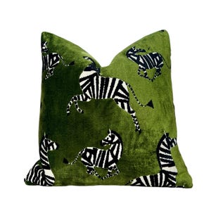 May include: Green velvet cushion with a black and white zebra print. The cushion features a repeating pattern of zebras in various poses.