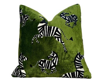 Op de afbeelding: Een groen fluwelen kussen met een zwart-wit zebraprint. Het kussen heeft een herhalend patroon van zebra's in verschillende poses.
