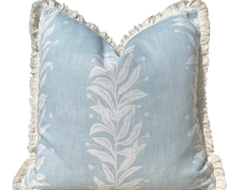 May include: A light blue throw pillow with a white floral pattern and a white fringe border.