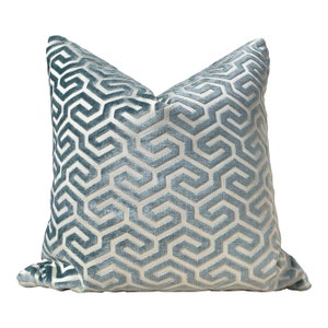 May include: A light blue throw pillow with a white geometric pattern. The pillow is made of a soft, velvety fabric.