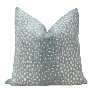 May include: A light blue throw pillow with a white and light blue patterned design. The pattern resembles a spotted animal print.