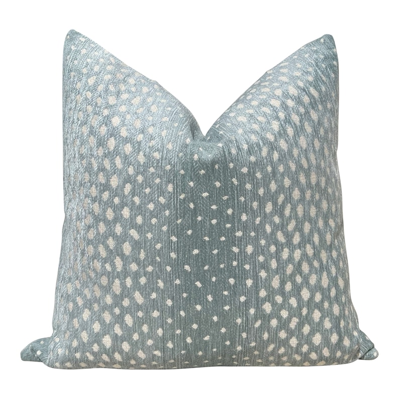 May include: A light blue throw pillow with a white and light blue patterned design. The pattern resembles a spotted animal print.
