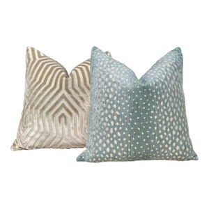 May include: Two decorative throw pillows, one with a geometric pattern in gold and beige, and the other with a white and blue patterned design.