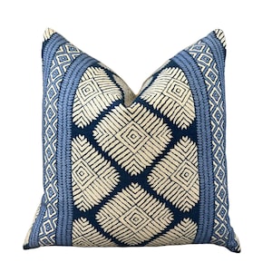 Puede incluir: Una almohada de tiro azul y blanco con un dise&ntilde;o geom&eacute;trico. La almohada tiene un borde azul claro con un patr&oacute;n de diamantes blancos.