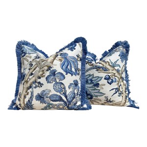 Pu&ograve; includere: Due cuscini decorativi blu e bianchi con bordi a frangia. I cuscini presentano un motivo floreale con accenti blu e marroni.