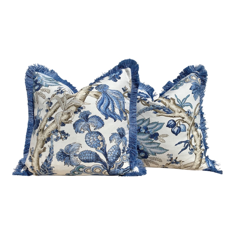 Pu&ograve; includere: Due cuscini decorativi blu e bianchi con bordi a frangia. I cuscini presentano un motivo floreale con accenti blu e marroni.