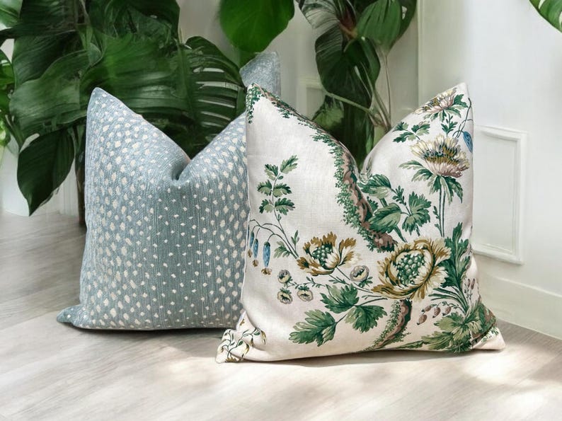 May include: Two decorative throw pillows, one with a blue and white geometric pattern and the other with a white background and a green floral design.