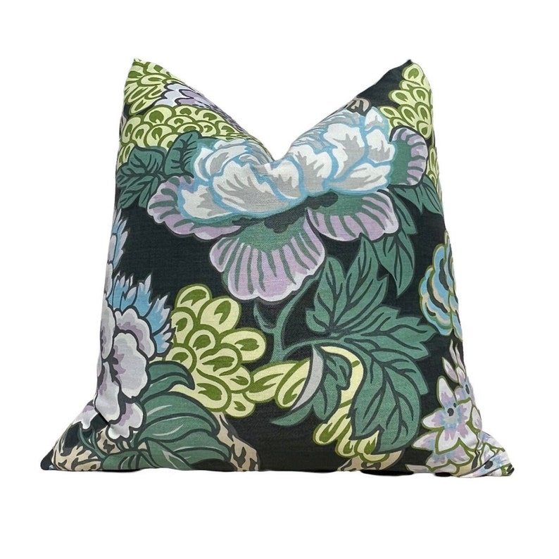 May include: A black pillow with a floral pattern in shades of green, purple, and white. The flowers are large and have a painterly style.