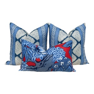 Puede incluir: Tres almohadas decorativas con un patr&oacute;n geom&eacute;trico azul y blanco y un patr&oacute;n floral azul y rojo.