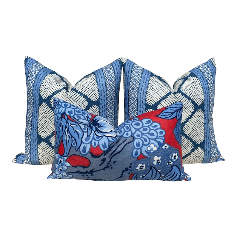 Puede incluir: Tres almohadas decorativas con un patr&oacute;n geom&eacute;trico azul y blanco y un patr&oacute;n floral azul y rojo.