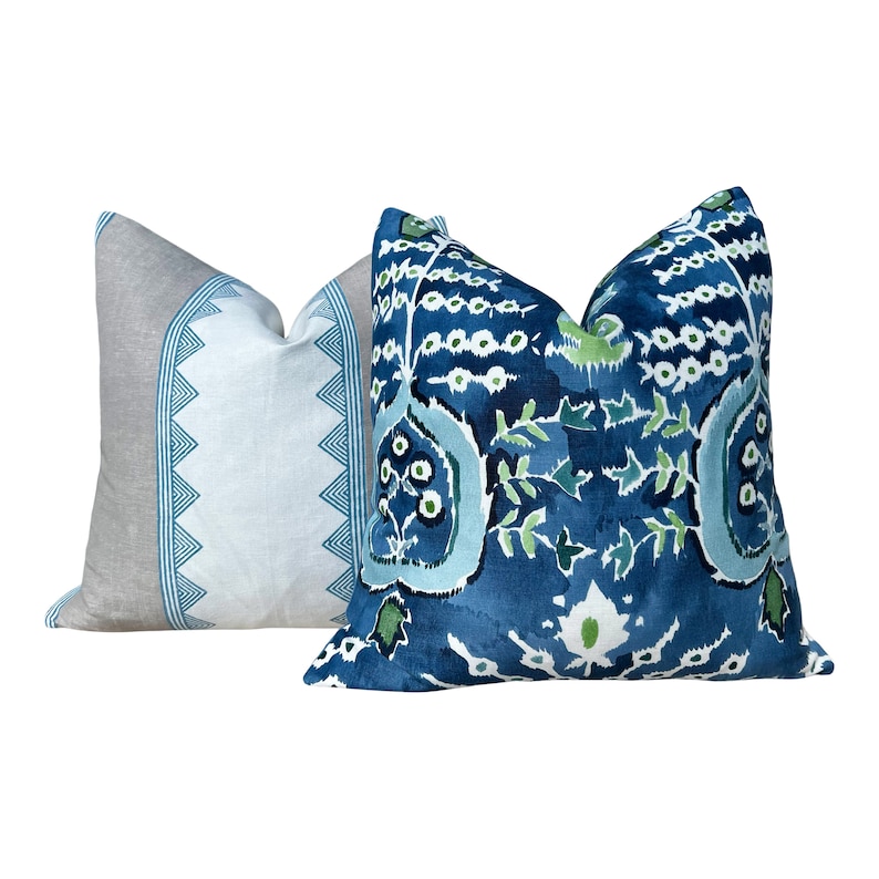 May include: Two decorative throw pillows with a blue and green floral pattern. The pillow on the left is a light blue and gray with a geometric pattern. The pillow on the right is a dark blue with a more intricate floral pattern.
