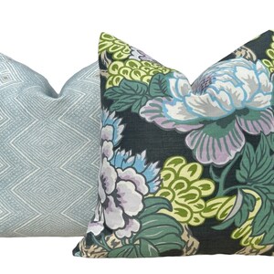 May include: Two decorative throw pillows, one with a blue and white geometric pattern and the other with a floral pattern in shades of green, blue, and purple on a black background.
