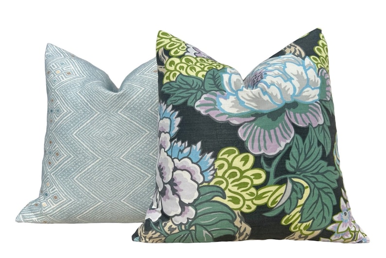 May include: Two decorative throw pillows, one with a blue and white geometric pattern and the other with a floral pattern in shades of green, blue, and purple on a black background.