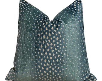 Può includere: Un cuscino decorativo quadrato con un motivo a pois verde acqua e bianco. Il cuscino ha una consistenza morbida e vellutata e un retro di colore neutro. Il design a pois è distribuito uniformemente sulla superficie.