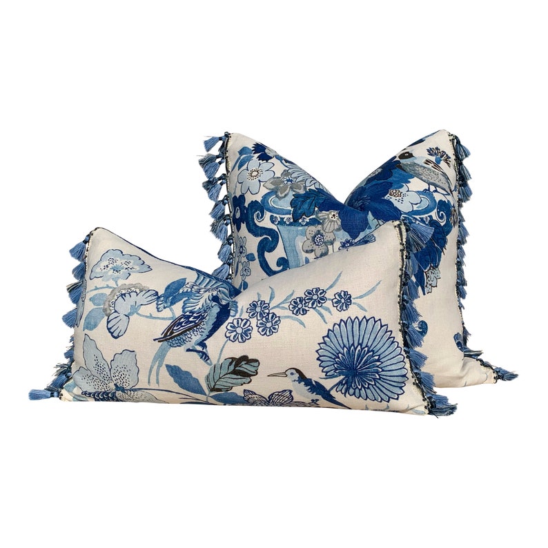 May include: Two blue and white patterned throw pillows with tassel trim. The pillows feature a floral and bird design.