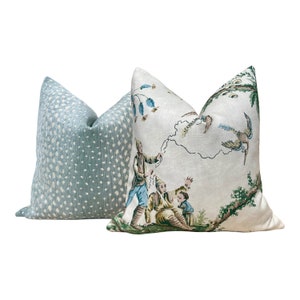 May include: Two decorative throw pillows. One pillow is light blue with white polka dots. The other pillow is white with a green and blue pattern of people flying kites.