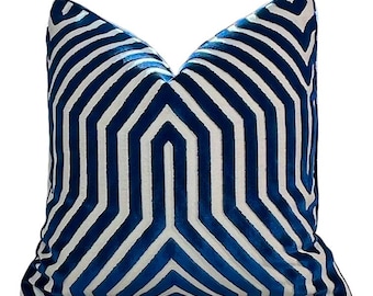 Puede incluir: Una almohada de tiro con estampado geométrico azul y blanco. La almohada está hecha de una tela de terciopelo suave y mullida.