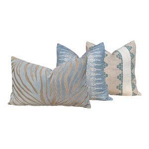 May include: Three decorative throw pillows in various designs. One pillow features a light blue background with tan zebra stripes. Another has a light blue background with a white and blue pattern. The third pillow has a beige background with a teal and white design.