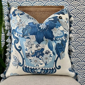 May include: Blue and white floral pillow with tassel trim. The pillow features a vase with flowers and butterflies.
