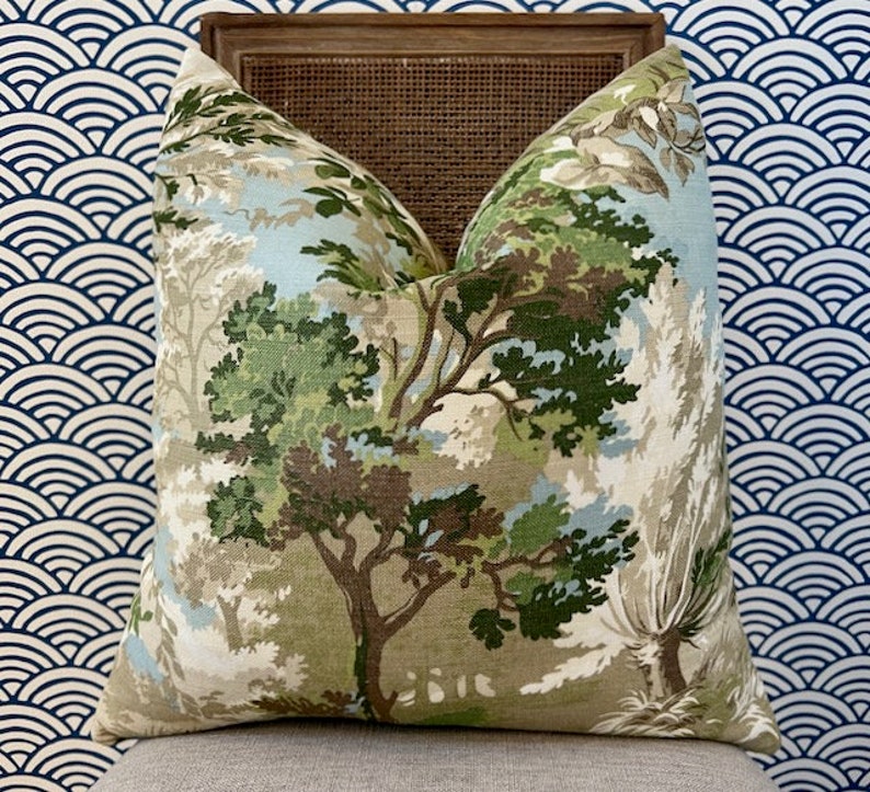 Puede incluir: Una almohada decorativa con un estampado de bosque verde, marr&oacute;n y blanco. La almohada est&aacute; hecha de una tela suave y texturizada y presenta una variedad de &aacute;rboles y follaje.