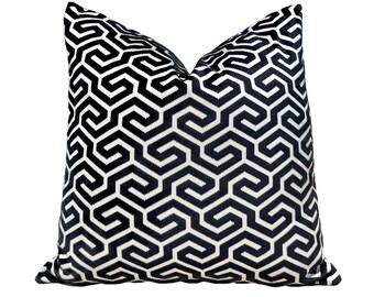 May include: Black and white geometric patterned throw pillow. The pillow is made of a soft, velvety fabric and features a repeating pattern of interlocking shapes.