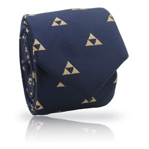 Puede incluir: Corbata enrollada azul marino con un patrón repetido de triángulos color beige. La corbata está hecha de una tela suave y se muestra sobre un fondo blanco. Los triángulos están espaciados uniformemente en la superficie de la corbata.