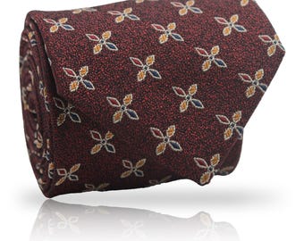 May include: Rolled burgundy tie with a repeating pattern of small, four-petal floral designs in yellow, blue, and red. The tie has a textured appearance and is displayed on a white background.