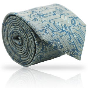Könnte beinhalten: Aufgerollte blaue Krawatte mit einem Leiterplattenmuster in Hellbeige. Die Krawatte besteht aus glänzendem Stoff und wird auf weißem Hintergrund mit Spiegelung präsentiert.