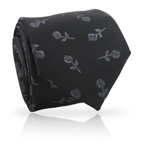 May include: Rolled black necktie with a repeating pattern of gray rose illustrations. The tie is made of a smooth fabric and is suitable for formal or business attire. The tie is rolled up, showing its full length.