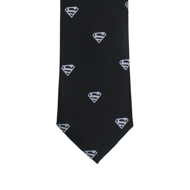 K&ouml;nnte beinhalten: Schwarze Krawatte mit einem sich wiederholenden wei&szlig;en Superman-Logo-Muster. Diese Krawatte ist ein klassisches Accessoire, das f&uuml;r formelle oder halbformelle Anl&auml;sse geeignet ist. Das Superman-Logo ist ein stilisiertes "S" in einem Diamanten.