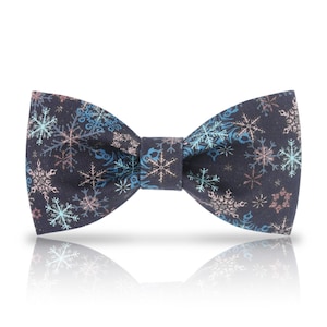 Puede incluir: Una pajarita azul oscuro con un patrón de copos de nieve en tonos azules y rosas.