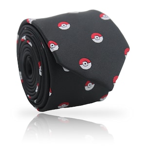 May include: A rolled-up black necktie featuring a repeating pattern of red and white circular designs. The tie is made of a smooth fabric and is displayed against a white background, with a subtle reflection visible below.