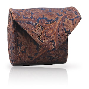 Può includere: Cravatta piegata con motivo paisley nei toni blu navy e marrone. La cravatta, realizzata in tessuto strutturato, è presentata su sfondo bianco. Il design dettagliato aggiunge un tocco di eleganza, ideale per occasioni formali.