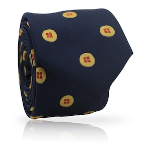 Op de afbeelding: Gerolde marineblauwe stropdas met een herhalend patroon van gele cirkels, elk met een rood vierkant. De stropdas is gemaakt van een gladde stof en wordt gepresenteerd op een witte ondergrond.