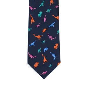 May include: Navy blue necktie with a repeating pattern of colorful dinosaurs in orange, pink, blue, and green. The tie is a classic shape, suitable for formal or casual wear.