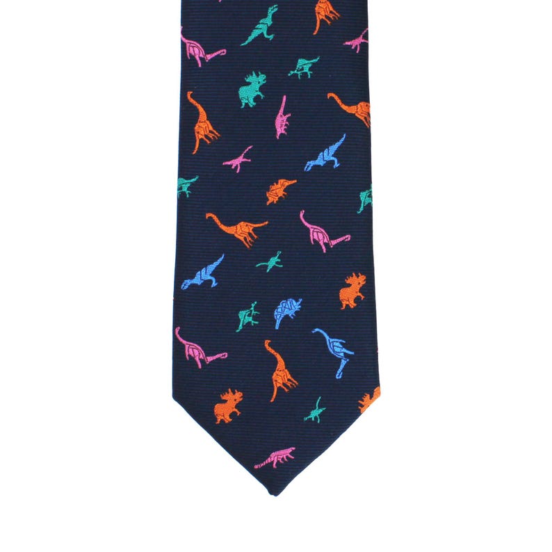 May include: Navy blue necktie with a repeating pattern of colorful dinosaurs in orange, pink, blue, and green. The tie is a classic shape, suitable for formal or casual wear.