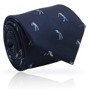 May include: Rolled navy blue tie featuring a repeating pattern of golfers in white and light blue. The tie is made of a smooth fabric and is suitable for formal or casual wear. The tie is rolled up, showing the pattern and texture.