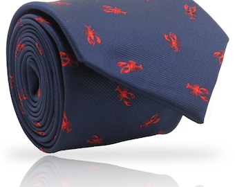 Puede incluir: Corbata azul marino enrollada con un patrón repetido de langostas rojas. La corbata está hecha de una tela suave. El diseño de la langosta añade un toque náutico al accesorio. La corbata está enrollada, mostrando el patrón y la textura.