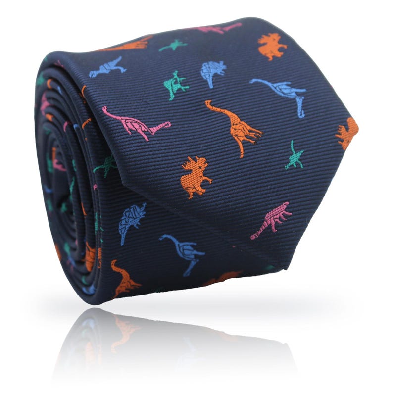 May include: A rolled navy blue tie featuring a repeating pattern of colorful dinosaurs in orange, pink, green, and blue. The tie is made of a smooth fabric and is suitable for formal or casual wear.