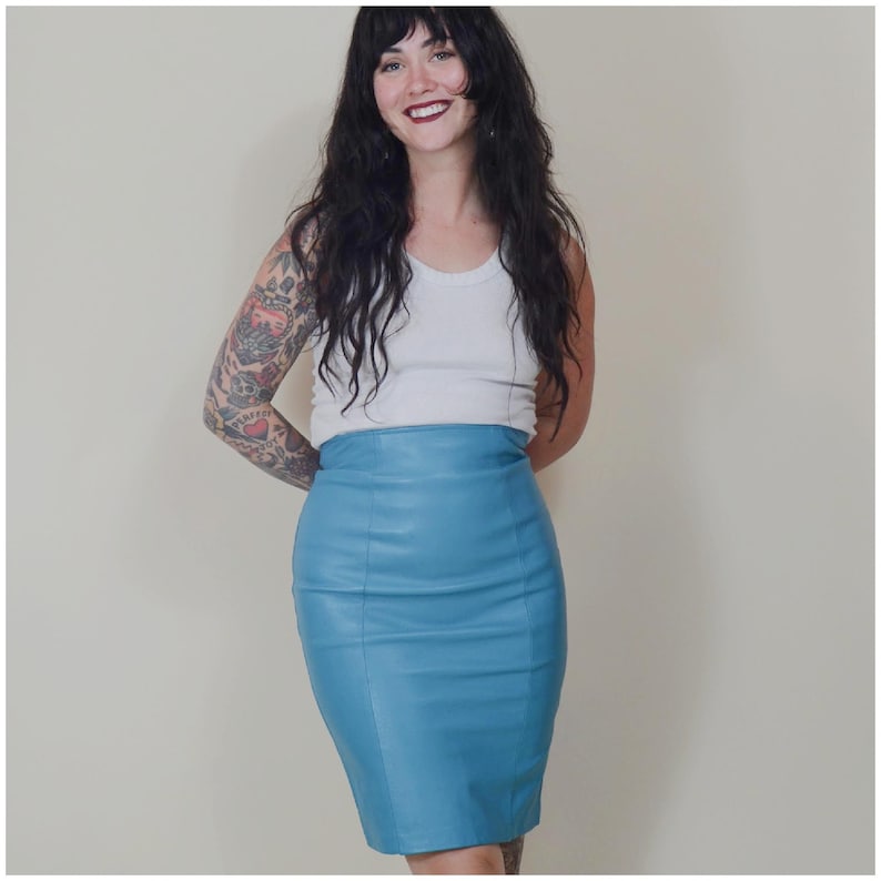 May include: A light blue pencil skirt. The skirt is made of a smooth material and has a high waist. The skirt is knee-length and has a fitted silhouette. The skirt is a solid colour and has a simple design.